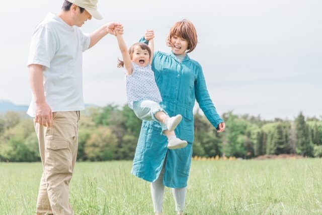 お母さんとお父さんが、子供と手を繋いでいる画像